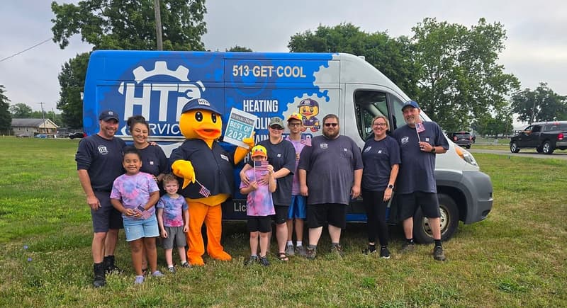 Team, children and duck mascot beside branded service van